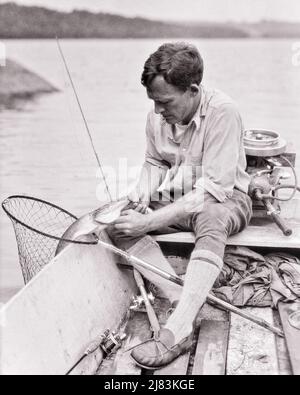 1920S UOMO A ESCA CASTING PESCATORE SEDUTO IN BARCA TOGLIENDO IL GANCIO DAL PESCE CATTURATO INDOSSANDO BRAGHE CALZINI DI LANA GAMBALETTO MOCASSINO - A455 HAR001 HARS FULL-LENGTH PERSONE MASCHI GANCIO ATLETICO ASTA B&W OBIETTIVI ABILITÀ ATTIVITÀ HOBBY AVVENTURA ANGOLO ALTO INTERESSE PER IL TEMPO LIBERO RIMOZIONE HOBBY CONOSCENZA TEMPO DI RICREAZIONE CATTATO ASPO PIACERE MOTORI FUORIBORDO MOTORE ELEGANTE ANGLING MOCASSINI LANA CASTING METÀ-ADULTO UOMO RELAX GIOVANE UOMO ADULTO ESCA BIANCO E NERO BRECHES ETNIA CAUCASICA GODIMENTO HAR001 VECCHIO STILE Foto Stock