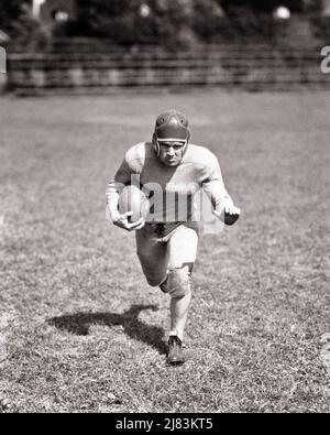 1930S CALCIO GIOCATORE CHE CORRE ALLA MACCHINA FOTOGRAFICA CHE PORTA LA PALLA DETERMINATA FEARSOME ESPRESSIONE FACCIALE INDOSSANDO CASCO IN PELLE - F7912 HAR001 HARS MASCHI ATLETICA FIDUCIA B&W OCCHIO CONTATTO OBIETTIVI FORZA CORAGGIO LEADERSHIP POTENTE OPPORTUNITÀ DI RICREAZIONE ATLETI CONCETTUALI DETERMINATO PAUROSO PALLE DA CALCIO GIOVANE ADULTO UOMO AMERICANO CALCIO NERO E BIANCO ETNIA CAUCASICA HAR001 VECCHIO STILE Foto Stock