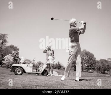 1970S COPPIA SENIOR SUL CAMPO DA GOLF DONNA IN PIEDI DA GOLF CART UOMO IN PRIMO PIANO TEEING OFF - G8117 HAR001 HARS NOSTALGIA VECCHIA MODA RITIRATO 1 FITNESS STILE AMICO SANO EQUILIBRIO CONCORRENZA FORTE ATLETA STILE DI VITA FEMMINE SPOSATO CONIUGE RURALE MARITI SALUTE COPIA SPAZIO AMICIZIA FULL-LENGTH SIGNORE FISICA FITNESS PERSONE CURA MASCHI GOLF ATLETICA PENSIONE FIDUCIA ANZIANO UOMO ANZIANO ADULTO DI MEZZA ETÀ B&W PARTNER UOMO DI MEZZA ETÀ ANZIANO DONNA DATANTE RETIREE ATTIVITÀ CORSO FELICITÀ FISICA DONNA DI MEZZA ETÀ GOLFERS TEMPO LIBERO FORZA LOW ANGLE RICREAZIONE ATTRAZIONE CONNESSIONE Foto Stock