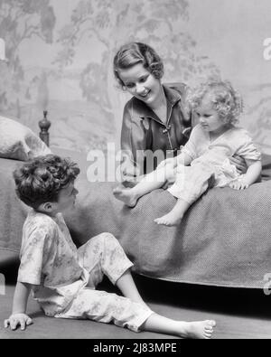 1930S DONNA SORRIDENTE MADRE CON FIGLIO RAGAZZO E FIGLIA TUTTI CON PIGIAMA CHE VANNO A DORMIRE A LETTO - J4094 HAR001 HARS DORMIRE SUBURBANO MADRI VECCHIO TEMPO NOSTALGIA FRATELLO VECCHIO MODO SORELLA 1 STILE NOVELLINO FIGLI PIACERE FAMIGLIE JOY LIFESTYLE FEMMINE READY BROTHERS STUDIO SHOT HEALTHINESS HOME VITA COPIA SPAZIO MEZZA LUNGHEZZA SIGNORE FIGLIE PERSONE MASCHI PIGIAMA SERENITY FRATELLI SORELLE OBIETTIVI B&W FELICITÀ BENESSERE ALLEGRO E BASSO ANGOLO FRATELLO SORRISI GIOIOSO CRESCITA ELEGANTE GIOVANI MOMS TOGETHERNESS BIANCO E NERO ETNIA CAUCASICA HAR001 VECCHIO STILE Foto Stock