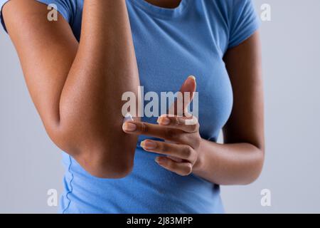 Metà della metà della donna africana americana dell'adulto che applica unguento sull'avambraccio, spazio di copia Foto Stock