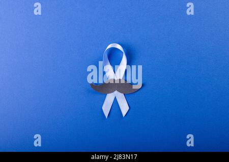 Direttamente sopra lo scatto del nastro blu di consapevolezza del cancro della prostata con baffi di carta su sfondo blu Foto Stock