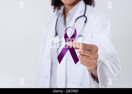 Sezione centrale del medico femminile di metà dell'adulto africano americano che tiene il nastro viola di consapevolezza del cancro Foto Stock
