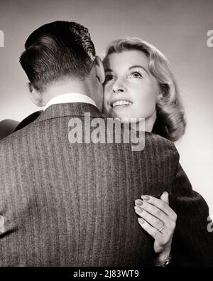 1950S 1960S ROMANTICA COPPIA VISTA POSTERIORE DI UOMO CHE ABBRACCIA UNA DONNA BIONDA SORRIDENTE - R6173 HAR001 HARS ABBRACCIO FORTE COMPIACIUTO GIOIA LIFESTYLE SODDISFAZIONE FEMMINE SPOSATO STUDIO SHOT CONIUGE MARITI COPIA SPAZIO AMICIZIA ABBRACCIO SIGNORE PERSONE CURA MASCHI ABBRACCIARE PARTNER B&W. SOGNI FELICITÀ TESTA E SPALLE ALLEGRO ORGOGLIO RELAZIONI VISTA POSTERIORE SORRISI CONNESSIONE CONCETTUALE DA DIETRO AMICHEVOLE ALLEGRO ELEGANTE ATTACCAMENTO PERSONALE AFFETTO INDIETRO VISTA COOPERAZIONE EMOZIONE MEDIO-ADULTO UOMO MEDIO-ADULTO UNIONE MATRIMONIO ANELLO MOGLI BIANCO E NERO ETNIA CAUCASICA HAR001 VECCHIO STILE Foto Stock