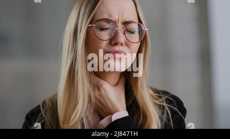 Donna di affari caucasica ragazza in occhiali direttore tenuta gola interna sente disagio mal di gola malattia respiratoria covid sintomo panico Foto Stock