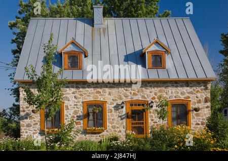 Replica del vecchio 1700s francese regime cottage stile fieldstone casa con tetto di lamiera grigio in estate. Foto Stock