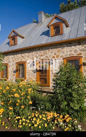 Replica del vecchio 1700s francese regime cottage stile fieldstone casa con tetto di lamiera grigio in estate. Foto Stock