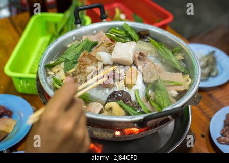 Carne, funghi e culantro assortiti (eryngium) cucinati su focaccine thailandesi (maw fai) in un ristorante self-service a Bangkok, Thailandia. Foto Stock