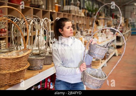 Ragazza che sceglie i cestini di vimini in deposito Foto Stock