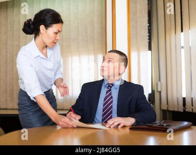 Documenti per la firma di uomini d'affari portati dalla partner femminile nella sala riunioni Foto Stock