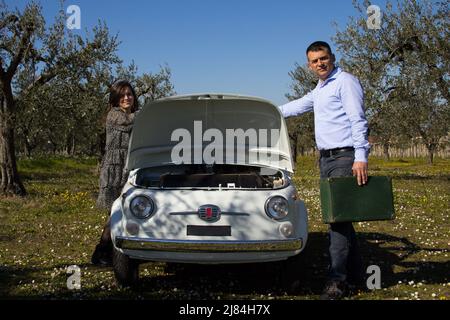 Giovane coppia caricando le valigie su un'auto d'epoca per la partenza di una vacanza. Foto Stock