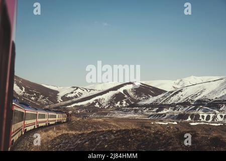 Erzincan, Turchia - 22 febbraio 2022: Treno espresso orientale e colline nevose nella stagione invernale. Foto Stock