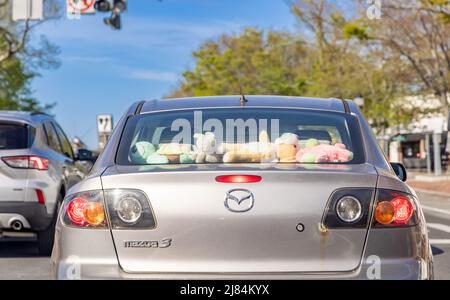 Mazada 3 con una finestra posteriore piena di giocattoli imbottiti per bambini Foto Stock