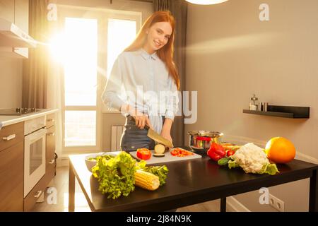 ragazza zenzero rossa in arancione sportivo top reggiseno mangiare salat in serata luce solare sfondo Foto Stock