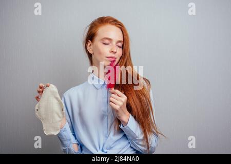 zenzero redhaired capelli lunghi donna che tiene eco-friendly guarnizioni organiche fatto di bio-cotone e tampon.making monouso scelta Foto Stock