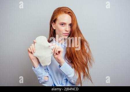 zenzero redhaired capelli lunghi donna che tiene eco-friendly guarnizioni organiche fatto di bio-cotone e tampon.making monouso scelta Foto Stock
