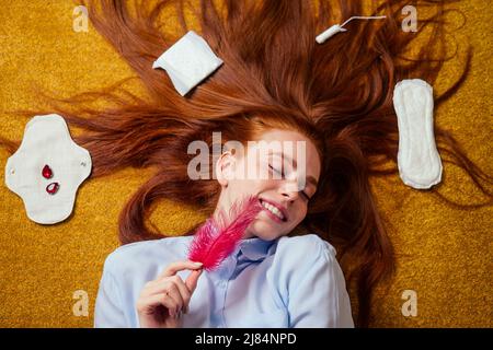 zenzero rosso capelli lunghi donna sdraiati a terra con eco-friendly guarnizioni organiche in bio-cotone e monouso tampon.making scelta Foto Stock