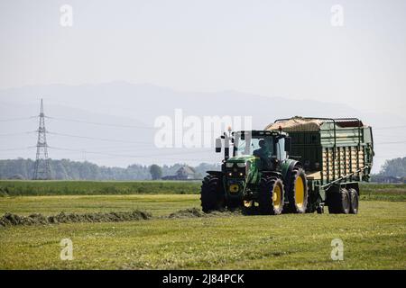 Kranj, Slovenia. 12th maggio 2022. Un agricoltore utilizza un carro da foraggio per raccogliere erba da macina per insilato a Zabnica. Dopo aver falciato l'erba un giorno prima, un agricoltore sloveno è riuscito a rastrellare l'erba e a raccoglierla per insilare il giorno successivo, che è insolitamente veloce. Ciò è stato reso possibile dalle alte temperature che hanno raggiunto i 30 gradi Celsius il 12 maggio 2022. Credit: SOPA Images Limited/Alamy Live News Foto Stock