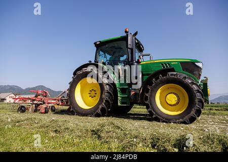 Kranj, Slovenia. 12th maggio 2022. Un agricoltore rastrema erba maltrattata a Zabnica. Dopo aver falciato l'erba un giorno prima, un agricoltore sloveno è riuscito a rastrellare l'erba e a raccoglierla per insilare il giorno successivo, che è insolitamente veloce. Ciò è stato reso possibile dalle alte temperature che hanno raggiunto i 30 gradi Celsius il 12 maggio 2022. Credit: SOPA Images Limited/Alamy Live News Foto Stock