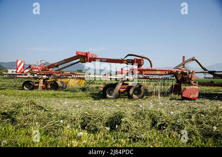 Kranj, Slovenia. 12th maggio 2022. Un agricoltore rastrema erba maltrattata a Zabnica. Dopo aver falciato l'erba un giorno prima, un agricoltore sloveno è riuscito a rastrellare l'erba e a raccoglierla per insilare il giorno successivo, che è insolitamente veloce. Ciò è stato reso possibile dalle alte temperature che hanno raggiunto i 30 gradi Celsius il 12 maggio 2022. Credit: SOPA Images Limited/Alamy Live News Foto Stock