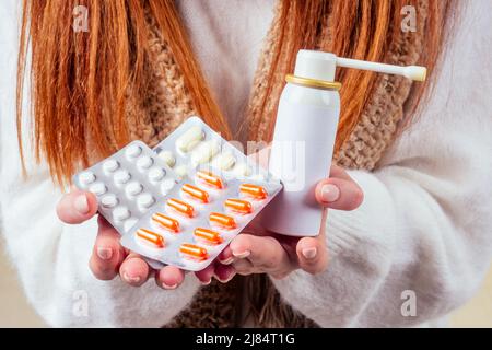 malbene rosso zenzero donna naso runny indossare maglione a maglia e sciarpa con molte pillole in mano in studio sfondo giallo Foto Stock