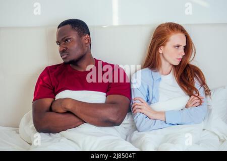 afro latino americano uomo e donna zenzero redhaired che si ignorano a vicenda dopo la lotta sul letto in camera da letto Foto Stock