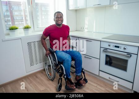 l'uomo latino ispanico si siede sulla sedia a rotelle a kichen e guarda la macchina fotografica Foto Stock