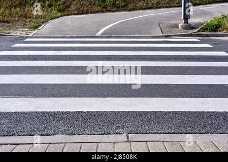 Attraversamento pedonale vuoto su strada asfaltata per attraversare la strada secondo le regole del traffico Foto Stock