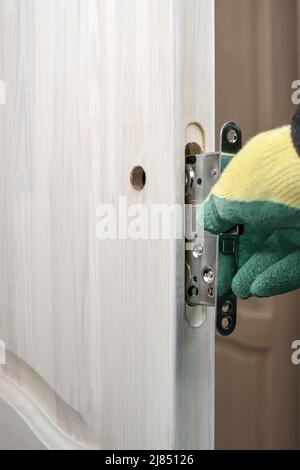 Installazione di una serratura su una porta di legno. Riparazione e sostituzione della serratura della portiera. Serratura di montaggio e inserimento in una porta di legno. Foto Stock