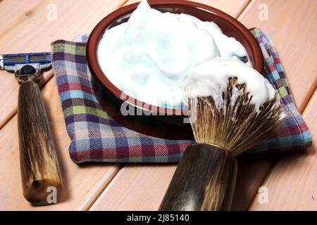 Attrezzatura di rasatura con lama di rasoio, spazzola e crema sul tavolo di legno. Attrezzi per l'igiene Foto Stock