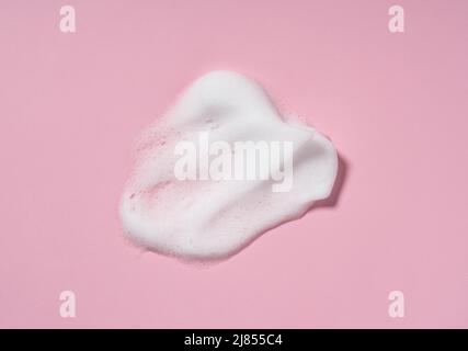Schiuma detergente per la pelle. Campioni di sapone, shampoo e schiuma detergente mousse con spazio copia su sfondo rosa. Primo piano della pulizia del viso Foto Stock