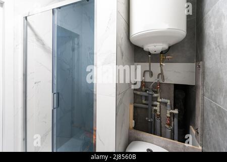 Tubi dell'acqua, valvole e manometri all'interno della casa, sistema con pompe elettriche e riscaldatori. Pipeline in metallo per caldaie domestiche, tubi caldi e freddi in servizio Foto Stock