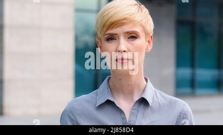 Primo piano femmina serio viso ritratto all'aperto caucasico medio invecchiato business donna boss bionda capelli corti leader indossa formale camicia infelice Foto Stock
