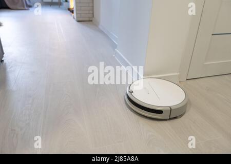 Robotica aspirapolvere sul laminato pavimento di legno smart la tecnologia di pulizia Foto Stock