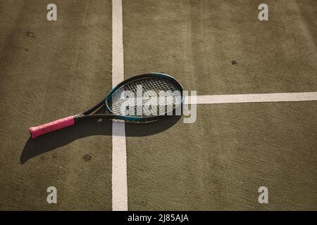 Vista ad angolo alto della racchetta da tennis su linee bianche al campo da tennis durante il tramonto, spazio per fotocopie Foto Stock