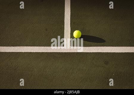 Vista ad angolo alto della palla da tennis gialla da linee bianche al campo da tennis durante il tramonto, spazio copia Foto Stock