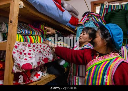 (220513) -- GONGSHAN, 13 maggio 2022 (Xinhua) -- la residenza di Dulong li Wenshi (fronte) e sua figlia organizzano coperte Dulong nel villaggio di Dizhengdang della Township di Dulongjiang, Gongshan Dulong e Contea autonoma di Nu, provincia di Yunnan della Cina sudoccidentale, 10 maggio 2022. Dulong è un gruppo etnico che vive in montagna nella Cina sudoccidentale. E' una delle nazionalità minoritarie meno popolose della Cina. Nel 2018, il gruppo etnico di Dulong ha sconvolto la povertà nel suo complesso, una svolta fenomenale. Li Wenshi, ereditando le abilità di tessitura della coperta di Dulong dalla madre, ha usato la sua esperienza per generare i vari prodotti Foto Stock