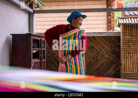 (220513) -- GONGSHAN, 13 maggio 2022 (Xinhua) -- il Dulong residente li Wenshi mette su una coperta di Dulong nel villaggio di Dizhengdang di Dulongjiang Township, Gongshan Dulong e Nu Autonomous County, la provincia di Yunnan della Cina sudoccidentale, 10 maggio 2022. Dulong è un gruppo etnico che vive in montagna nella Cina sudoccidentale. E' una delle nazionalità minoritarie meno popolose della Cina. Nel 2018, il gruppo etnico di Dulong ha sconvolto la povertà nel suo complesso, una svolta fenomenale. Li Wenshi, ereditando le abilità di tessitura della coperta di Dulong dalla sua madre, ha usato la sua perizia per generare i vari prodotti che sono popolari fra t Foto Stock