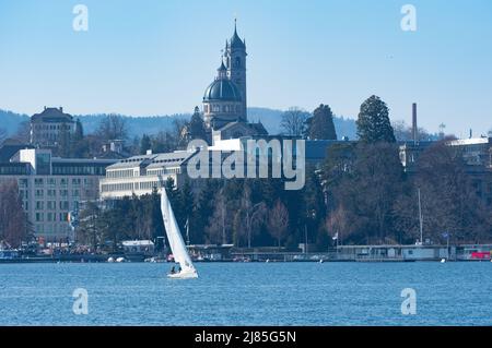 Zurigo, Svizzera - Marzo 5th 2022: una barca a vela che naviga di fronte allo skyline urbano Foto Stock