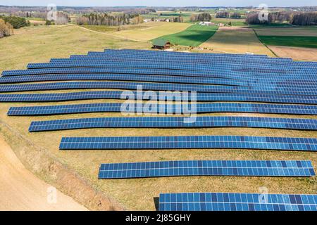 Vista aerea dell'azienda agricola solare, file di pannelli fotovoltaici da una piccola casa Foto Stock