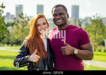 Primo piano della coppia interrazziale che tiene rosa bianca nel parco autunno di primavera Foto Stock
