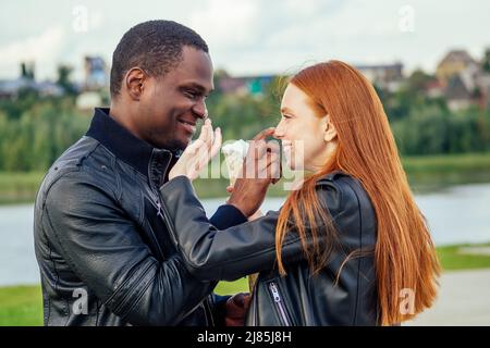 Diverse coppie multietniche che mangiano gelato nel parco primaverile autunnale Foto Stock