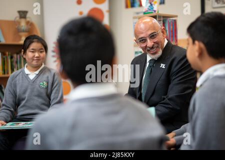 Il Segretario dell'Educazione Nadhim Zahawi legge il libro commemorativo del Giubileo con gli allievi dell'anno 5 durante una visita alla scuola elementare di Manor Park a Sutton. Data foto: Venerdì 13 maggio 2022. Foto Stock