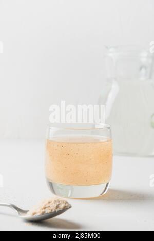 Fibra di psyllium in galss su sfondo bianco. Superfood per intestino sano e dieta senza glutine. Formato verticale. Foto Stock