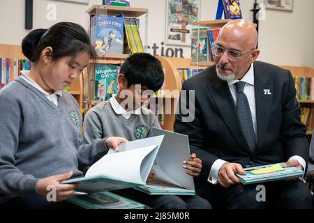 Il Segretario dell'Educazione Nadhim Zahawi legge il libro commemorativo del Giubileo con gli allievi dell'anno 5 durante una visita alla scuola elementare di Manor Park a Sutton. Data foto: Venerdì 13 maggio 2022. Foto Stock