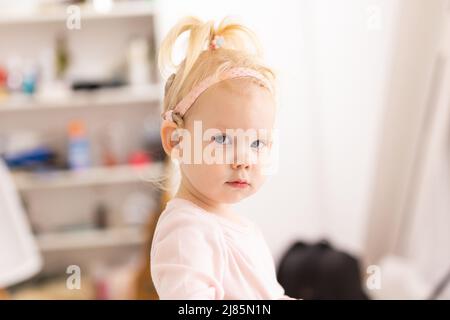 Bambino divertente con impianto cocleare a casa. Ascolta il concetto di tecnologia innovativa di aiuto e medicina Foto Stock