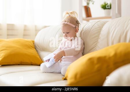 Bambino divertente con impianto cocleare seduto a casa. Ascolta il concetto di tecnologia innovativa di aiuto e medicina Foto Stock