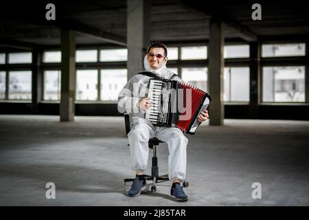 Il musicista suona l'armonica, la fisarmonica nella sala con colonne Foto Stock