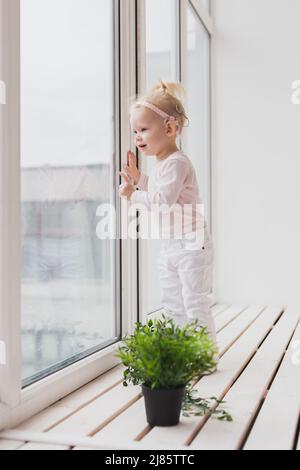 Bambino divertente con impianto cocleare seduta a casa e mangiare. Ascolta il concetto di tecnologia innovativa di aiuto e medicina Foto Stock