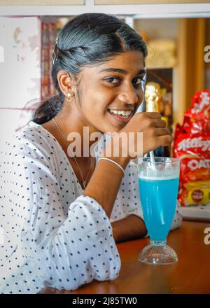 Ragazza adolescente indiana che beve softdrink di colore blu, Tangassery, Thangassery, Kerala, India. Foto Stock